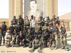 Wspólne zdjęcie komandosów GROM-u (z zasłoniętymi twarzami) i Navy SEAL przy portrecie Saddama Husajna / www.grom.mil.pl